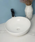 USZWBY Vessel Sinks Modern Simple Round Sink Home Bathroom Above Counter Basin with black faucet and white marble vase.
