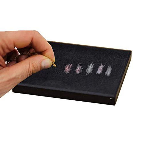 Close-up of Waytest 18K gold testing kit; hand holds small gold sample over black foam tray with color swatches.
