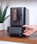 Top Shelf Wifi Automatic Espresso Machine With Built In Milk Frother And Adjustable Bean Grinder One Touch Brew In Under Ninety Seconds Matte Black on kitchen counter with plant in background.