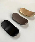 Assorted cabinet drawer handles including gold, black, and brown finishes on a light background; modern curved design.