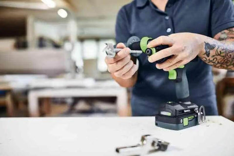 Person assembling a Badass Cordless Drill Driver Featuring Ec Tec Brushless Motor High Torque Heavy Duty Power Tool on a workbench.