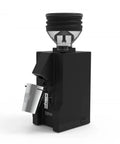 Premium Single Dose Espresso Coffee Grinder Stepless Micrometric Dial In Adjustment Comfort Grip Knob For True Baristas Dialing In Shots With Smooth Pulls And Rock Solid Consistency Pure Gloss Black Finish showing side view with grinder and cup.