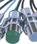 Various capacitive proximity sensors, metal cylindrical design, different colored caps, used in automation and industrial settings.
