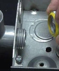 Hands installing Heavy Duty Two Inch Sealing Lock Nut For Electrical Conduit with yellow PVC gasket into metal electrical box.