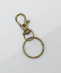 60 Pack Bronze Swivel Clasps Featuring Lanyard Snap Hooks With Key Rings Plus Lobster Claw Clips For Jewelry Making And Diy Crafts Hella Durable Zinc Alloy Construction Smooth 360 Spin Action Badass Quality That Lasts - close-up view of single clip with key ring.