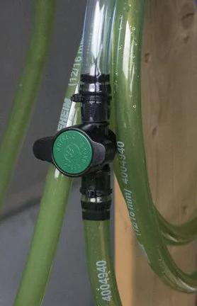 Inline barbed ball valve for 3/4 inch tubing with green knob, installed on translucent green tubing