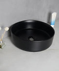 USZWBY Vessel Sinks Nordic Matte Black Round Art Sink Household Ceramic Above Counter Wash Basin with decorative items.