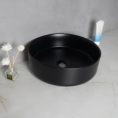 USZWBY Vessel Sinks Nordic Matte Black Round Art Sink Household Ceramic Above Counter Wash Basin with decorative items.