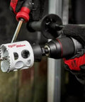 Milwaukee 4-1/8-inch ice-hardened hole saw attached to a drill, held by a gloved hand