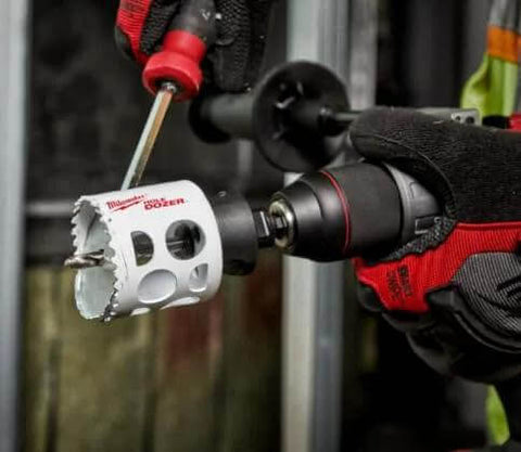 Milwaukee 4-1/8-inch ice-hardened hole saw attached to a drill, held by a gloved hand