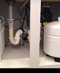 Under-sink RO system installed with two white filter housings and a white expansion tank.