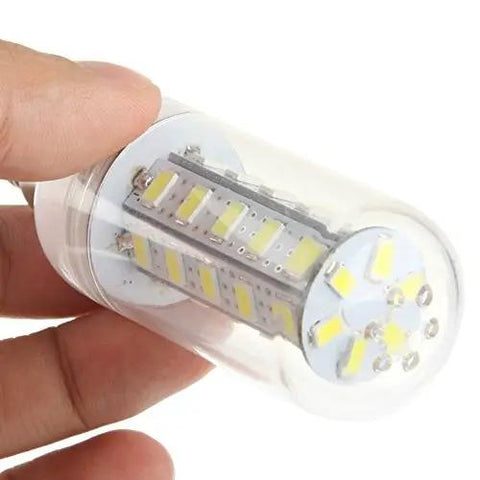 Compact LED light bulb in clear plastic casing held by a hand, showcasing its internal components and design for energy-efficient lighting.