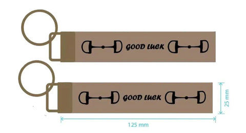 Pair of brown keychains with snaffle bit design, featuring 'Good Luck' text, measuring 125mm x 25mm.