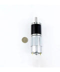 Heavy Duty 42mm Planetary Gear Motor With 775 Brushed DC Drive next to a coin for size comparison, showing its compact design.