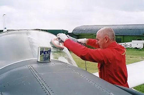 Man polishing airplane windshield with Multipurpose All In One Metal Cleaner And Polish For Chrome Aluminum Silverware Glass And Fiberglass Cleans Shines And Protects All Metals Fiberglass And Acrylics Home And Industrial Use 1000ml Can nearby.