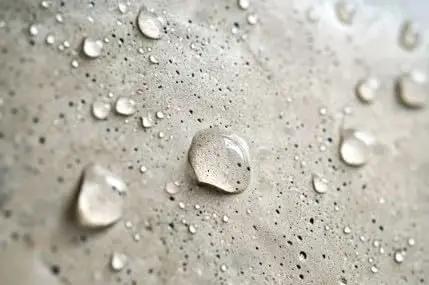 Close-up of water droplets on concrete surface treated with Concentrated Silane Siloxane Water Repellent For Concrete Brick And Masonry Surface Sealer Low Voc Penetrating Formula Big Time Protection That Holds Up Through Rough Days.