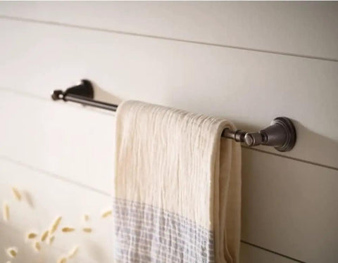 Wall-mounted towel bar with beige cloth draped over, highlighting metal finish and horizontal design against wooden wall panels.