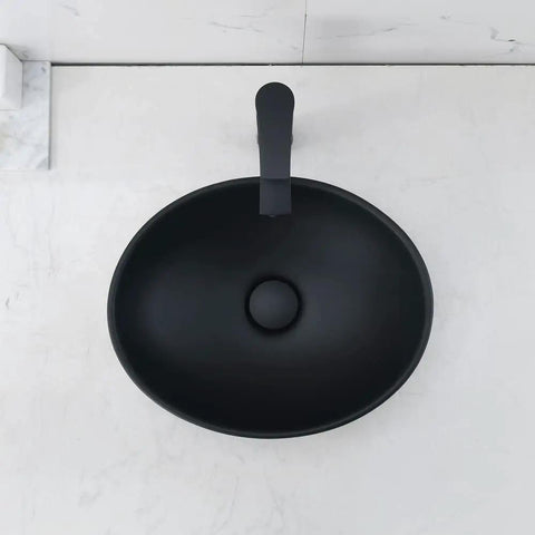 Top view of black oval vessel sink with faucet visually showing modern design, contrasting with light counter.