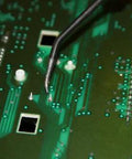Close-up view of a green automotive circuit board with solder pads and a white connector