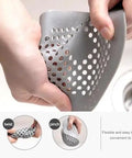A Total Game Changer 3 Pack Silicone Drain Catchers For Sink And Tub Reusable Hair Strainers shown in gray, flexible material being rinsed.