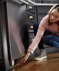 Woman installing Flo Smart Water Leak Detector 3 Pack, Home Water Sensor Alarm with real-time alerts under dishwasher for leak monitoring.