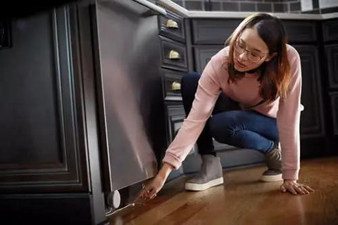 Woman installing Flo Smart Water Leak Detector 3 Pack, Home Water Sensor Alarm with real-time alerts under dishwasher for leak monitoring.