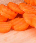 Orange crinkle-cut carrot slices on a wooden cutting board.