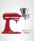 Front view of KitchenAid all-metal grain mill attachment mounted on a red stand mixer