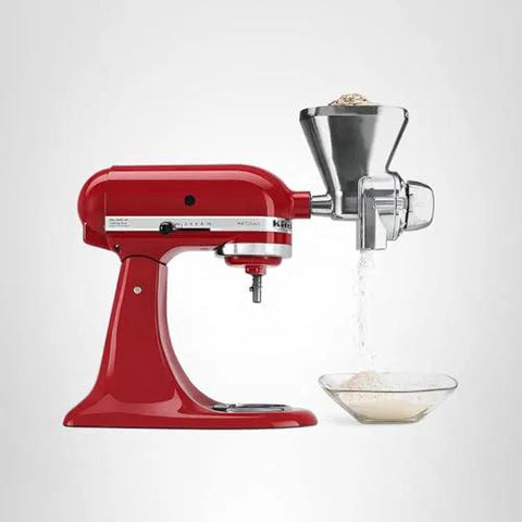 Front view of KitchenAid all-metal grain mill attachment mounted on a red stand mixer