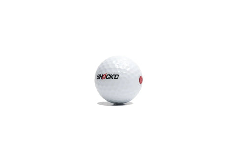 Shock'D prank golf ball with raised red button, labeled "Loudest Golf Ball Ever For Pranks, Viral Sleeve Of Three Novelty Balls With Red Button Hit"