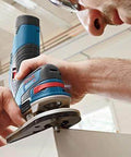 Bosch blue wood router in use; angled side view of handheld power tool with circular base plate