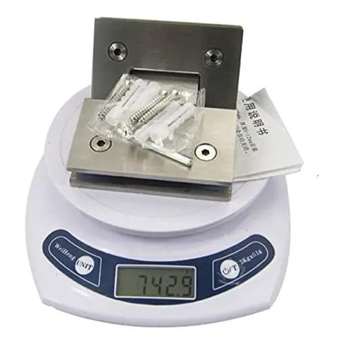 Close-up of stainless steel pivot hinge set for glass shower doors on scale, showing weight with included screws and manual.