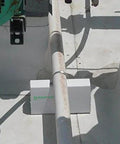 White 6-inch PVC rooftop pipe support block installed under a roof pipe on a flat roof; Amazon brand.