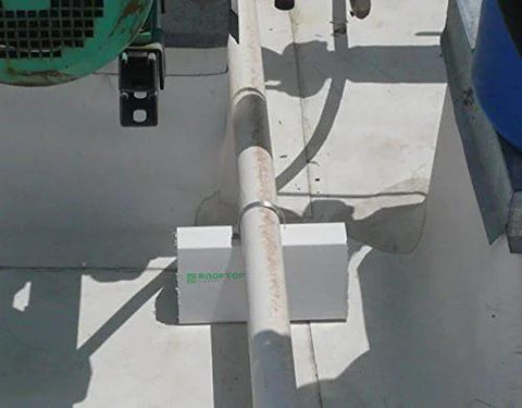 White 6-inch PVC rooftop pipe support block installed under a roof pipe on a flat roof; Amazon brand.