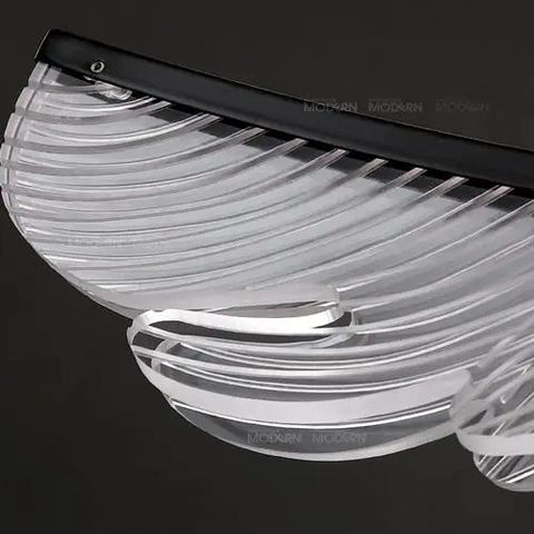 Close-up of a sleek modern linear pendant light with a curved transparent shade. Perfect for kitchen islands or dining tables.