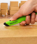 Westcott safety ceramic utility knife, green handle, cutting cardboard (close-up)