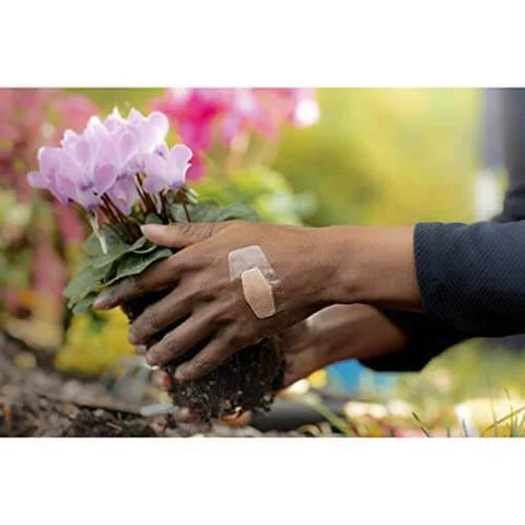 Person gardening with waterproof clear bandage on hand, demonstrating Waterproof Clear Bandages Assorted Sizes 100 Count With 360 Degree Seal.