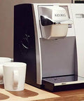 Office Pro Style Commercial Single Cup Coffee Maker With K Cup Pod Compatible, colorful touchscreen, on countertop, mugs beside.