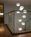Modern Round Glass Ball Chandelier With Long Stair Pendant Light Featuring Heavy Duty Steel Frame And Premium Glass Orbs For Easy Ceiling Setup And Killer Room Glow illuminating a hallway with clear spheres.