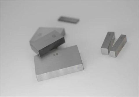 Heavy Duty 32 Piece Metric Gage Blocks And Parallel Gauge Set Forged From Bulletproof High Speed Steel showing 50mm and smaller blocks on white surface.