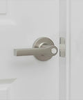 Close-up of a sleek silver door handle on a white door, showcasing its modern design and functionality.