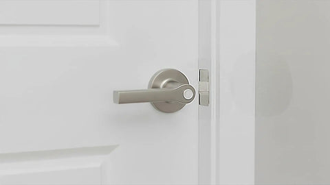 Close-up of a sleek silver door handle on a white door, showcasing its modern design and functionality.