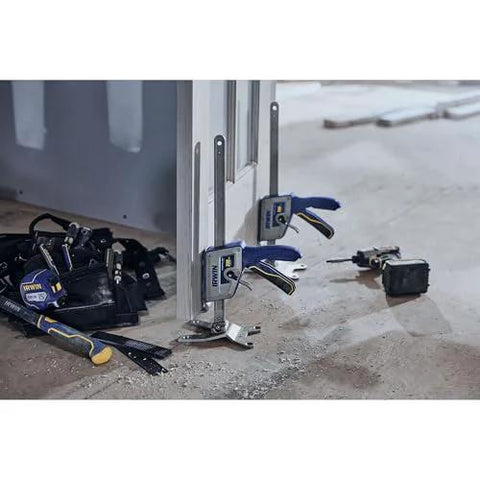 IRWIN Quick-Lift construction jacks with blue handles, three units leaning against a metal frame on a construction site.