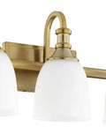 Richmond 3 Light Vanity Light in Aged Brass with Satin Opal Glass Shades, Steel Curved Arm Frame, Model 5011-3-80 in bathroom setting