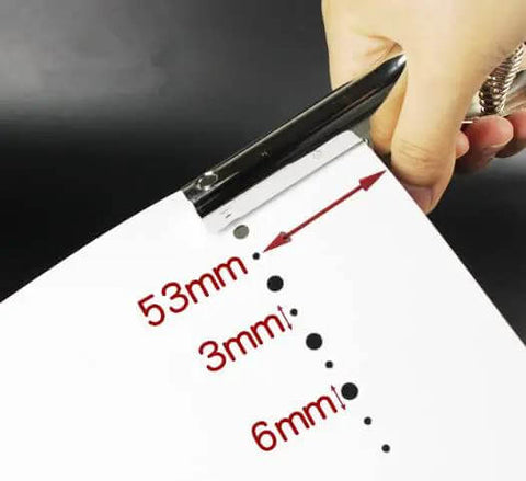 Hand using Tough As Nails Single Hole Punch For Crafts And Scrapbooks, Quarter Inch Hole Puncher In Zinc Alloy on white paper showing hole sizes.