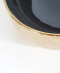 Close-up of a USZWBY Vessel Sinks Ceramic Vessel Sink with a sleek black bowl and textured gold rim for modern bathrooms.