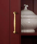Close-up of Antique Brass Cabinet Pull on red cupboard, showcasing vintage zinc alloy handle, 5 inch length, for kitchen and dressers.