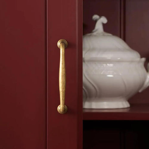 Close-up of Antique Brass Cabinet Pull on red cupboard, showcasing vintage zinc alloy handle, 5 inch length, for kitchen and dressers.