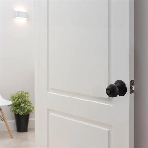 White door with Keyed Entry Ball Door Knob in Matte Black Finish with Brass Construction 2 Way Latch Anti Bump Technology visible