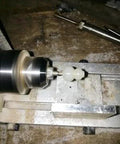 Mini wood lathe close-up turning a small light-colored workpiece between centers